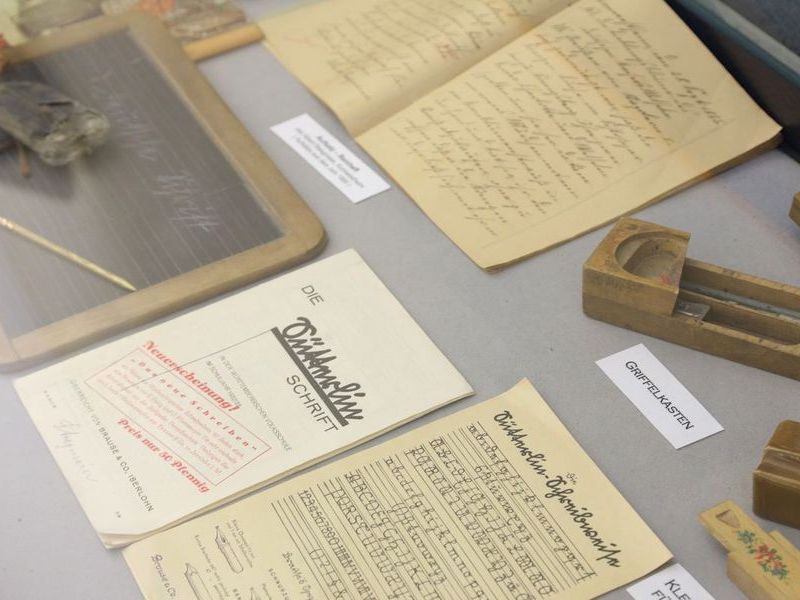 Dokumente mit früheren Schriften und Schreibutensilien in der Dauerausstellung.